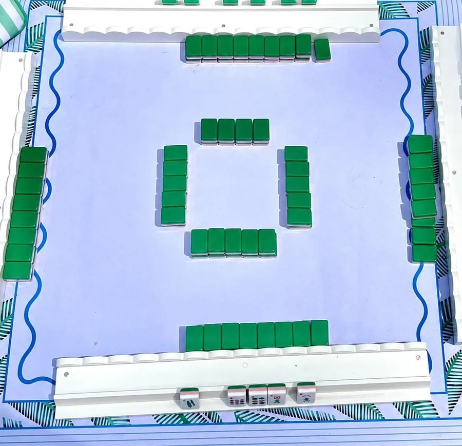 A complete Mahjong table with racks, green tiles and a mat, seen from above